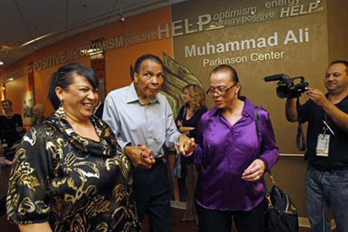 FILE - In this Feb. 22, 2012, file photo, Muhammad Ali, center, with the support of sister in-law Marilyn Williams, left, and wife Lonnie, walks through the Muhammad Ali Parkinson Center at Barrow Neurological Institute at St. Joseph's in Phoenix. Mohammed Ali is in the hospital with respiratory problems, and while officials haven't given details about his condition, the boxing great’s health in general is complicated by advanced Parkinson’s _ a degenerative disease he’s lived with for three decades. (AP Photo/The Arizona Republic, David Kadlubowski)