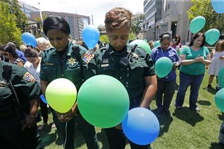 East Baton Rouge Sheriff's deputies Natasha Stingley, right, and Minnie Ducksworth, left, bow their heads in prayer before releasing balloons at a noon vigil organized by municipal court workers in downtown Baton Rouge, La., Wednesday, July 20, 2016, in honor of recent slain and injured sheriff deputies and police. Several police officers and sheriff deputies were killed and wounded Sunday morning in a shooting near a gas station in Baton Rouge, less than two weeks after a black man was shot and killed by police here, sparking nightly protests across the city. (AP Photo/Gerald Herbert)