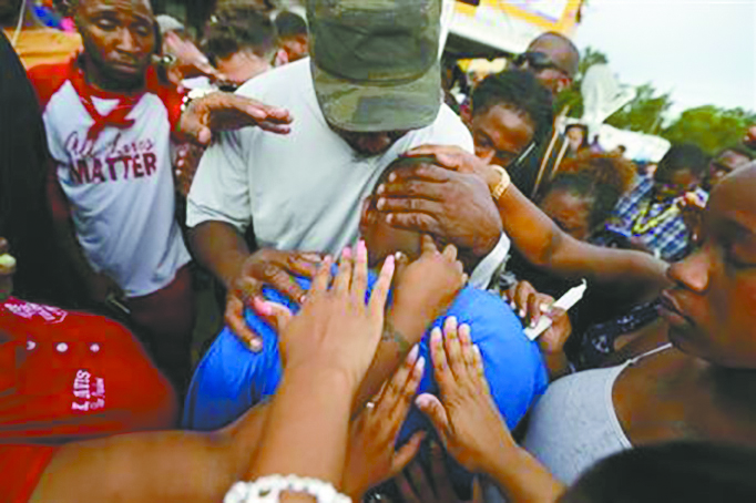 Cameron Sterling, son of Alton Sterling, who was killed by Baton Rouge police, is comforted by hands from the crowd at a vigil outside the Triple S convenience store in Baton Rouge, La., Wednesday, July 6. (AP Photo/Gerald Herbert) 