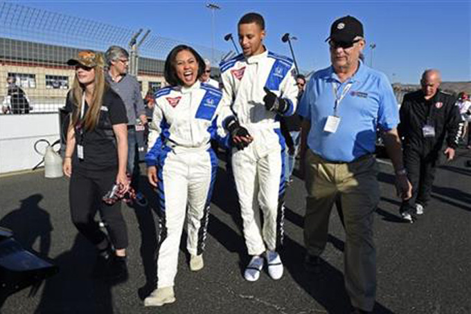 NBA basketball player Stephen Curry and his wife Ayesha Curry talk about their ride after experiencing a lap in a IndyCar driven by Mario Andretti before the Indy Grand Prix of Sonoma in Sonoma, Calif., Sunday, Sept. 18, 2016. Ayesha Curry is this year's Grand Marshal of the Grand Prix of Sonoma. (Jose Carlos Fajardo/Bay Area News Group via AP)