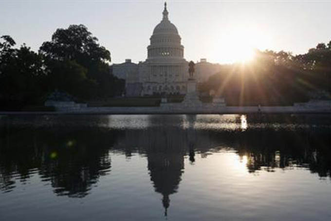 This Wednesday, Oct. 2, 2013 photo shows the Capitol building reflected in the Capitol Reflecting Pool at sunrise in Washington. The 2016 presidential campaign has underscored an economic paradox: Financially, black Americans and Hispanics are far worse off than whites, yet polls show minorities are more likely than whites to believe in the American Dream. And they are less anxious about the outcome of the election. (AP Photo/Carolyn Kaster)