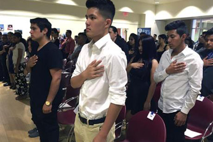 In this Aug. 19, 2016 file photo, Long Chi Vong, 16, center, from Albuquerque, and other immigrants stand for the U.S. Pledge of Allegiance before taking the Oath of Citizenship at a ceremony in Rio Rancho, N.M. San Francisco 49ers quarterback Colin Kaepernick recent refusal to stand for the National Anthem revealed deep differences in the way Americans of all stripes view patriotic symbols in a country founded on the freedom to protest. (AP Photo/Russell Contreras)