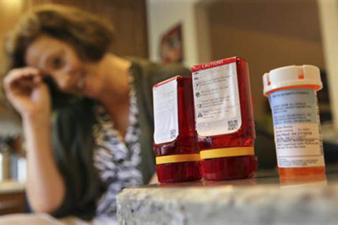 In this Sunday, Sept. 18, 2016, photo, Shelley Ewalt sits in her home, in Princeton, N.J., near an amber-colored CVS pharmacy prescription bottle, right, and two uniquely designed red ones from Target. After CVS took over operation of Target's drugstores earlier this year, distraught customers have been asking the drugstore chain to bring back the retailer’s red prescription bottles, which came with color-coded rings, labeling on the top and prescription information that was easier to read. Ewalt tweeted to the drugstore chain, asking if there was any chance they might return to the design of the Target bottles, which she found easier to open. (AP Photo/Mel Evans)
