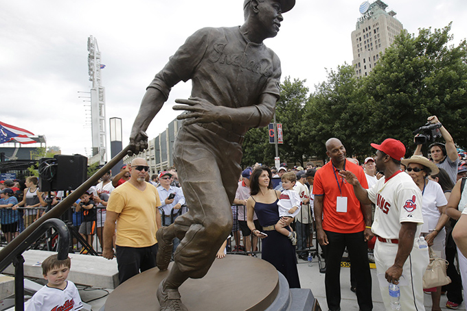 Larry Doby Jr., in red shirt, talks with Michael Bourn after the unveiling of a statue of Hall of Fame Larry Doby Saturday, July 25, 2015, in Cleveland. Doby broke the color barrier in the AL on July 5, 1947, just months after Jackie Robinson played for the Brooklyn Dodgers. Doby spent nine seasons with Cleveland and helped lead the Indians to a World Series title in 1948. He had a career .283 average with 253 homers. He led the league with 32 homers and 126 RBIs in 1954, when the Indians won 111 games. Before joining the Indians, Doby starred for Newark in the Negro League. He retired following the 1959 season. Doby's No. 14 was retired in 1994, 47 years after he was signed by Indians owner Bill Veeck. A seven-time All-Star, Doby died in 2003 at the age of 79. (AP Photo/Tony Dejak)