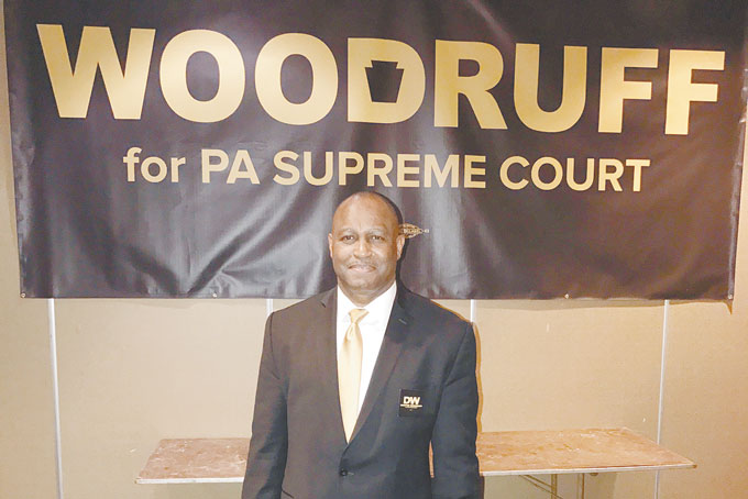 ENDORSED—Common Pleas Judge Dwayne Woodruff poses with a campaign banner in Harrisburg just after the PA Democratic Party endorses him for the state Supreme Court. (Photo by Joy Woodruff) 