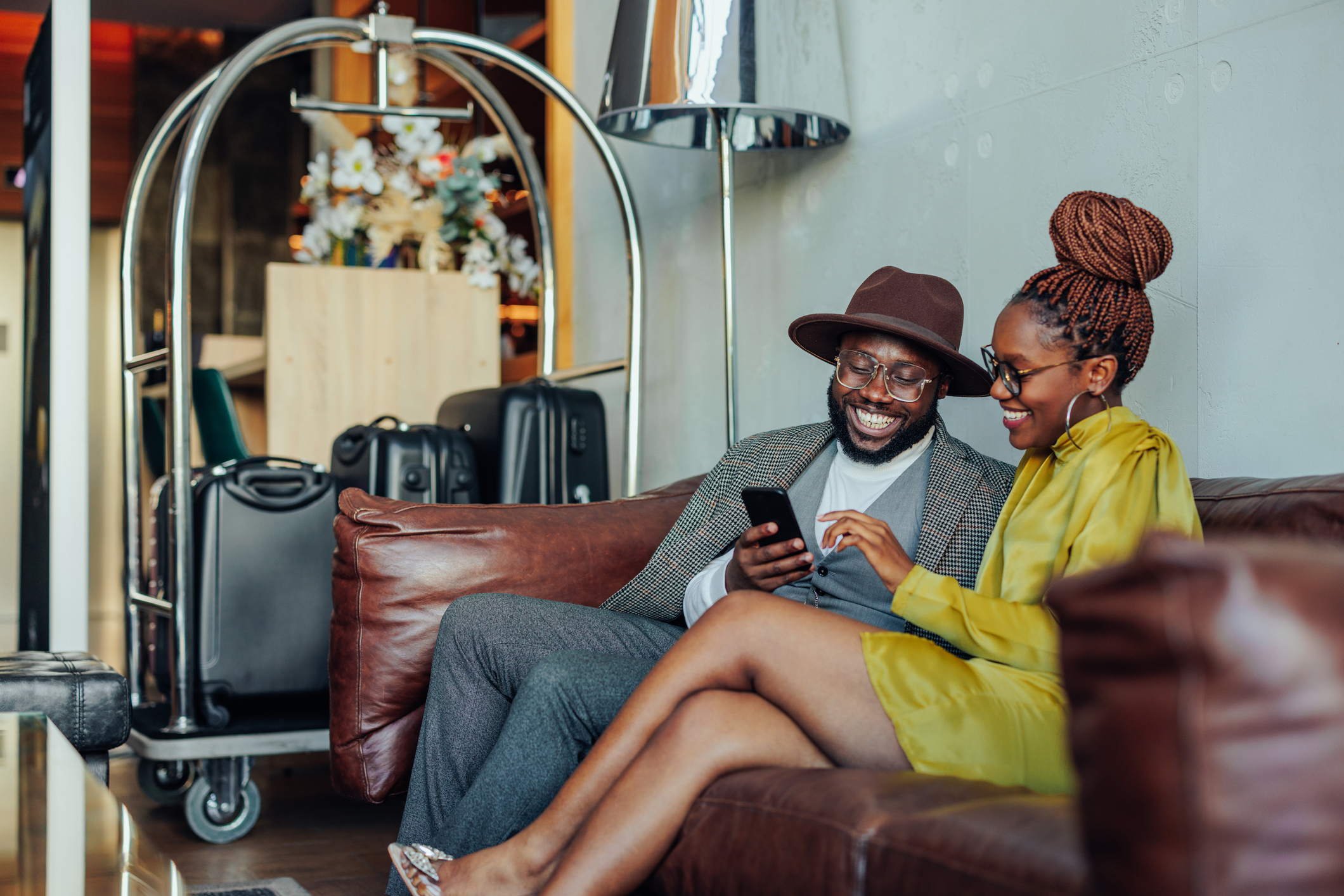 Wealthy couple with smartphone in hotel lounge.