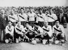 A black and white photo shows a group of men in soccer jerseys.
