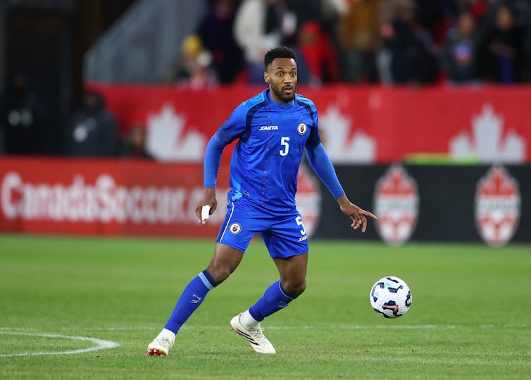 A man in blue kit controls a football.