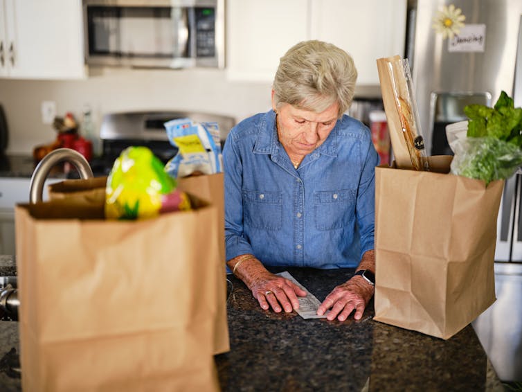 An older woman reviews her grocery purchases.