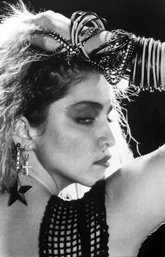 Madonna around the age of 25 wearing lots of cheap bangles and earrings.
