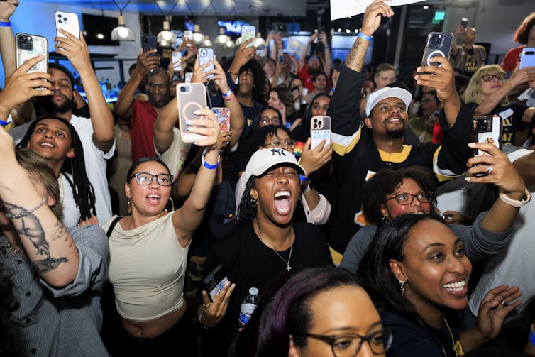 Many young and excited people celebrate at a large party.