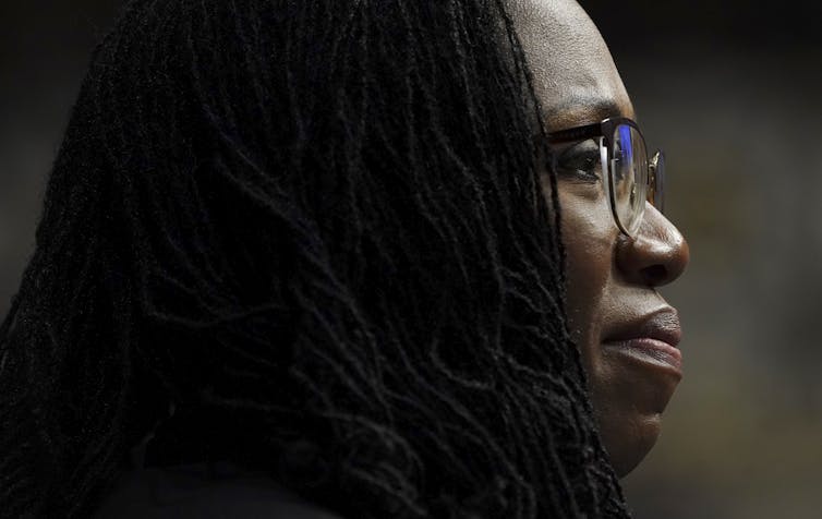 A close up profile view of a Black woman wearing glasses.